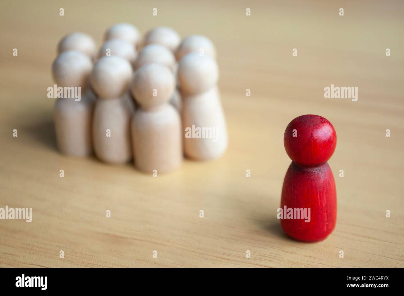 A single red wooden doll separated by other dolls. Representing either leadership or isolation Stock Photo