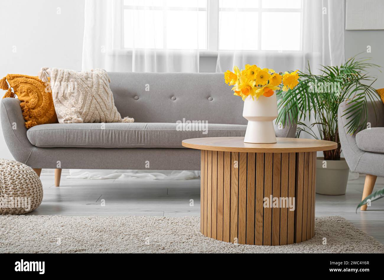 Interior of light living room with cozy sofa and flower vase on coffee ...