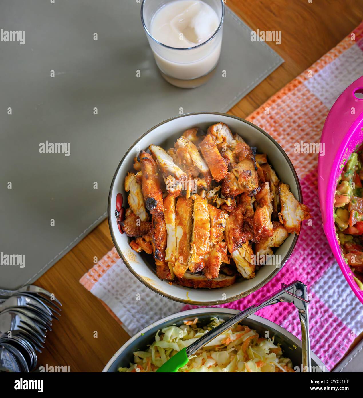 Roast chicken and cabbage coleslaw on the dinner table. Home cooking and entertainment concept. Stock Photo