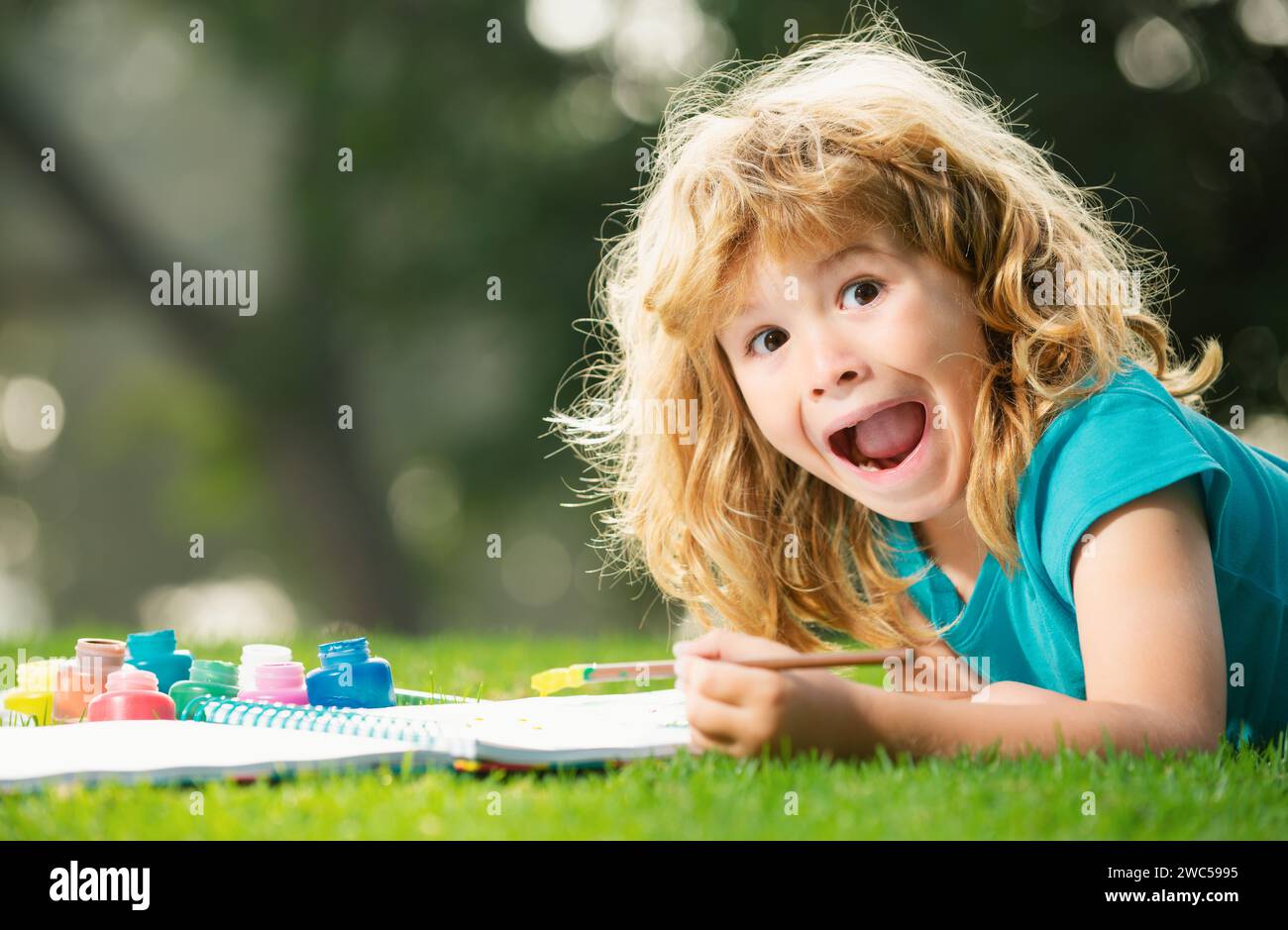 Excited Spring Excited kid painting in spring nature. Portrait of smiling happy kid ...