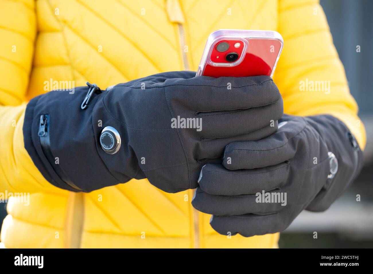 A woman wearing battery heated gloves during cold weather. The gloves have variable heat settings and help those suffering with Reynauds Disease Stock Photo