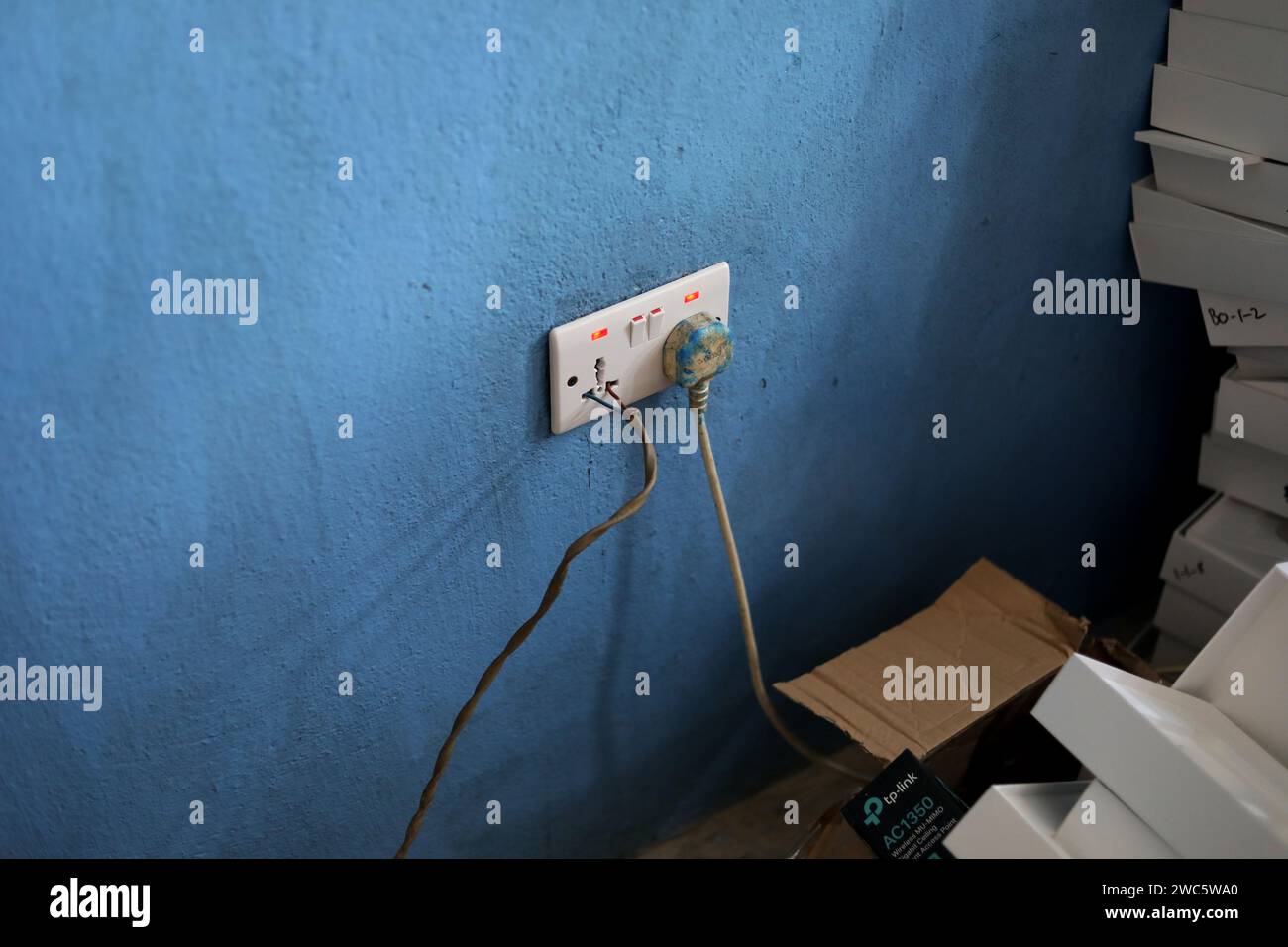 Extremely bad electrical practice with wires pushed into a plug socket in Bo, Sierra Leone, Africa. Stock Photo