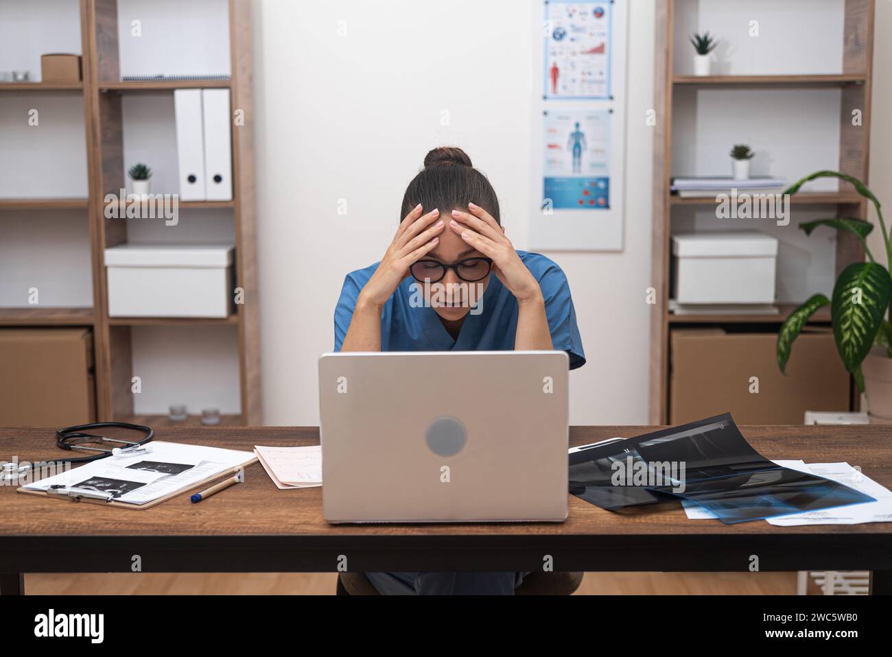 Pensive doctor solves complex issues regarding patient treatment resting head on hands tiredly Stock Photo