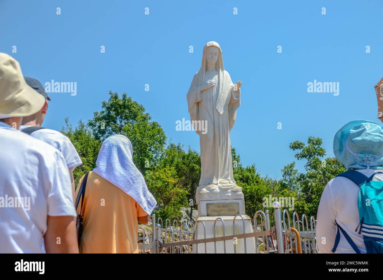 A group of Catholic pilgrims pray at a holy place. Pilgrims in Medjugorje, Bosnia and Herzegovina. Statue of Virgin Mary. Stock Photo
