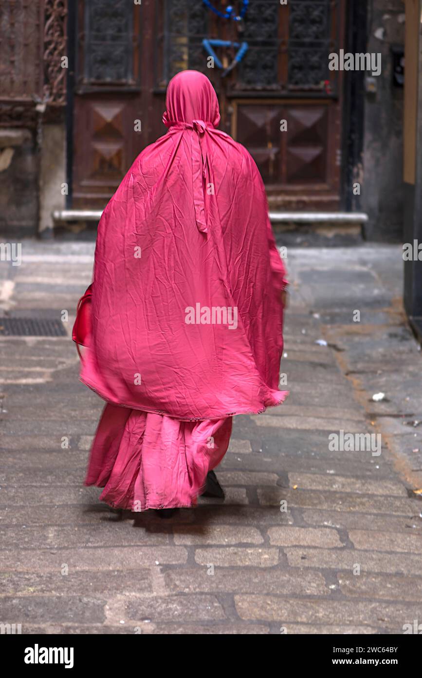 Woman with red robe in the streets of the historic centre, Genoa, Italy Stock Photo