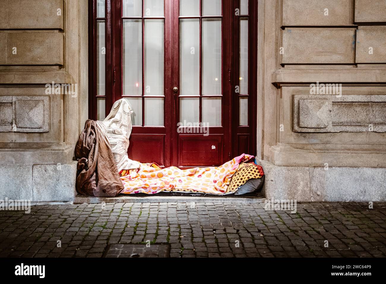 Illuminated bed of homeless person in front of urban house, Porto, Portugal Stock Photo