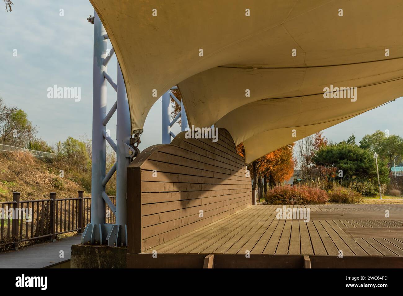 Closeup side view of wooden outdoor stage with white canvas awning in public park Stock Photo