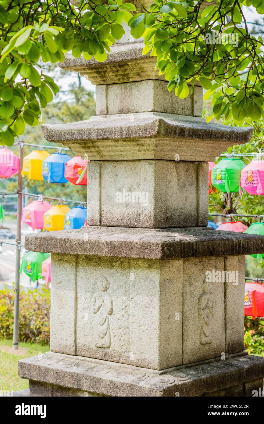 Stone carved pagoda under tree branches in front of colorful paper lanterns Stock Photo