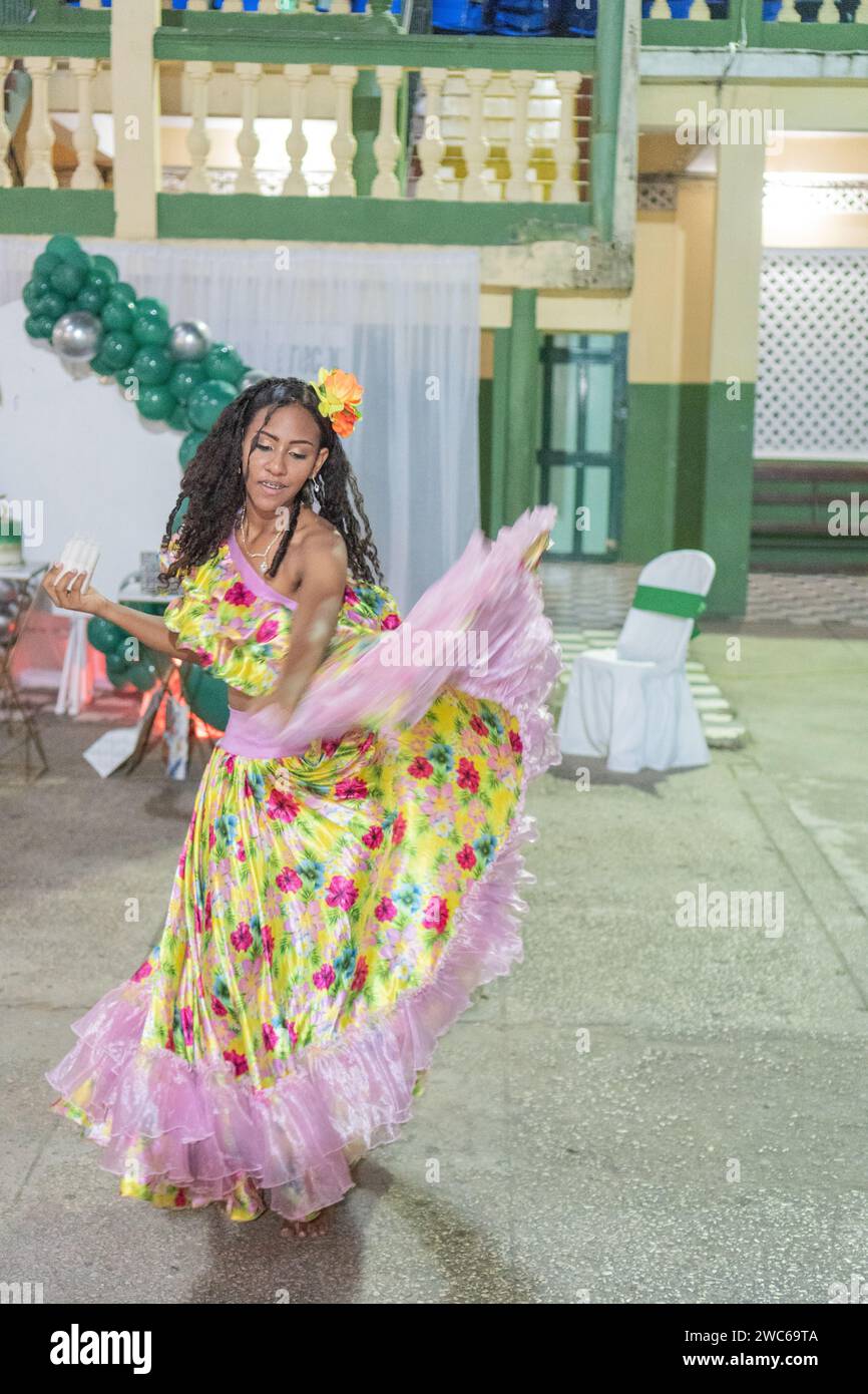 A woman dancing Cumbia, her floral skirt billowing, with a festive flower adorning her hair. Stock Photo