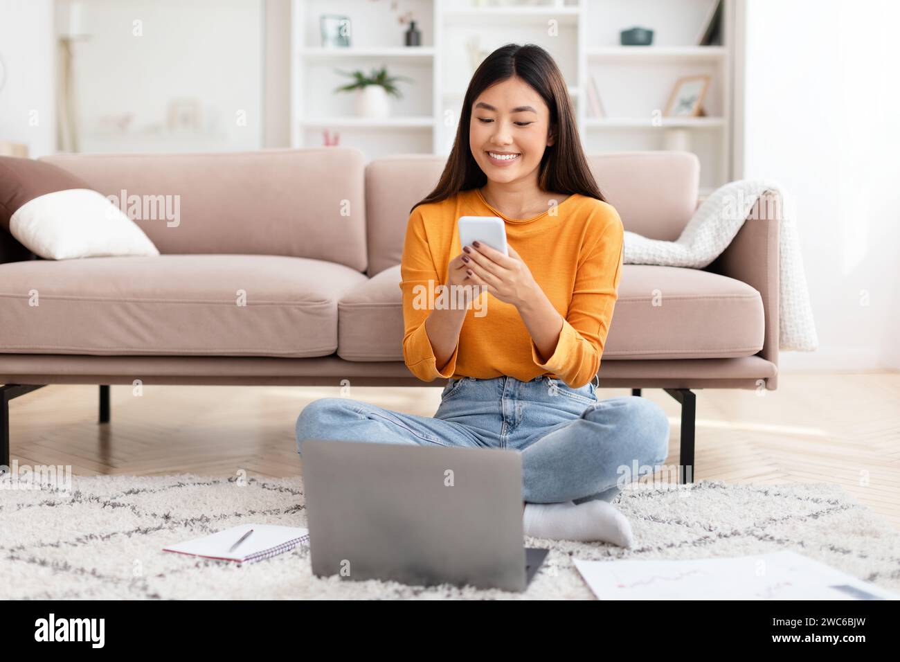 Pretty young asian lady entrepreneur using smartphone, home interior Stock Photo
