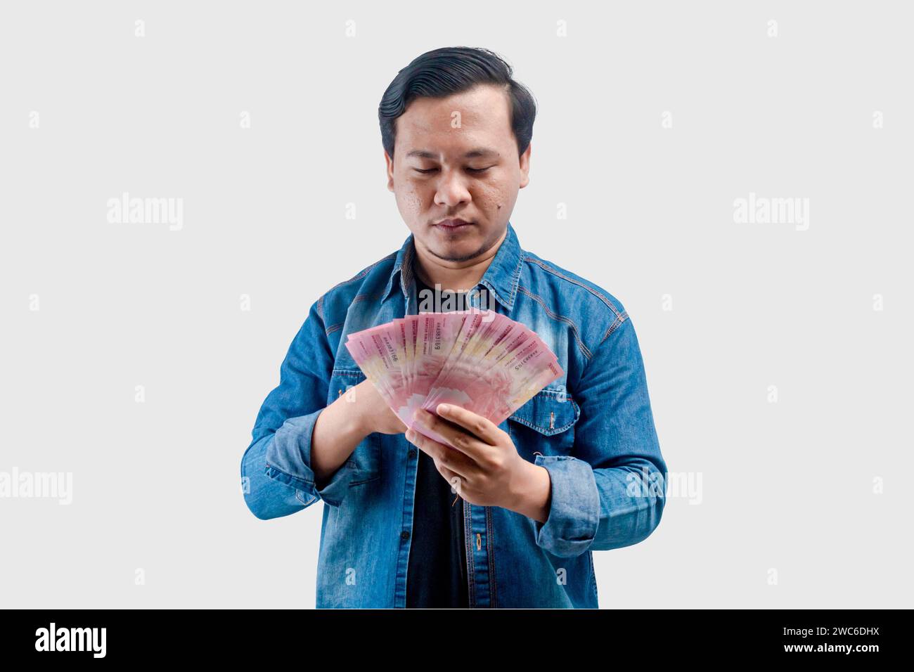 Young Asian man showing worried face expression while holding paper money Stock Photo