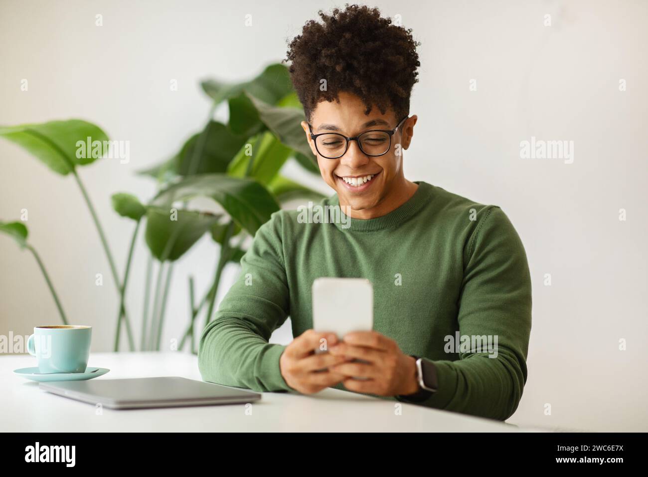 Happy young black guy freelancer working at cafe Stock Photo