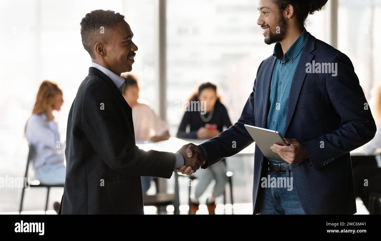 Two smiling black businessmen shaking hands after making good deal Stock Photo