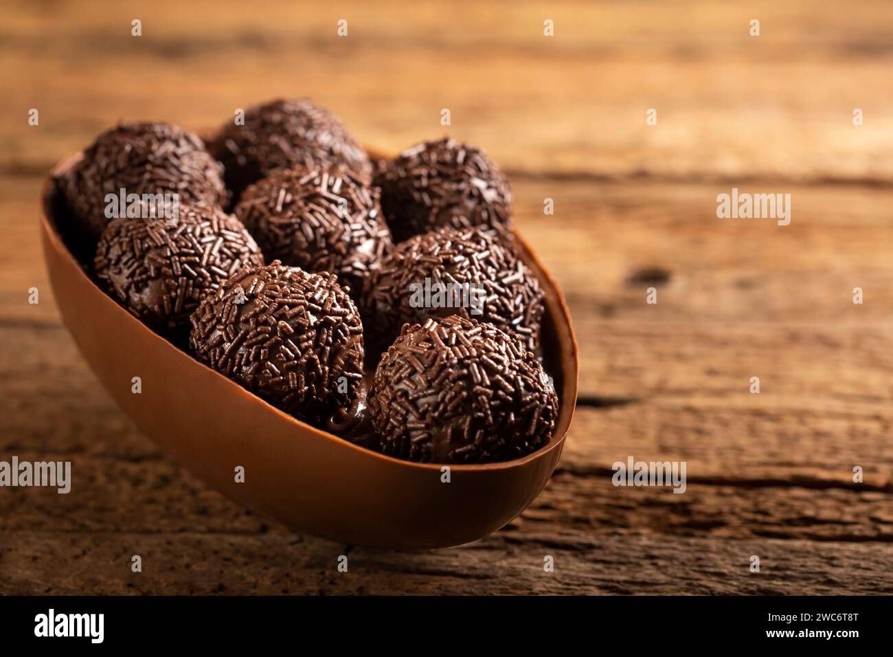 Chocolate Easter eggs stuffed with brigadiers on rustic wooden background. Stock Photo