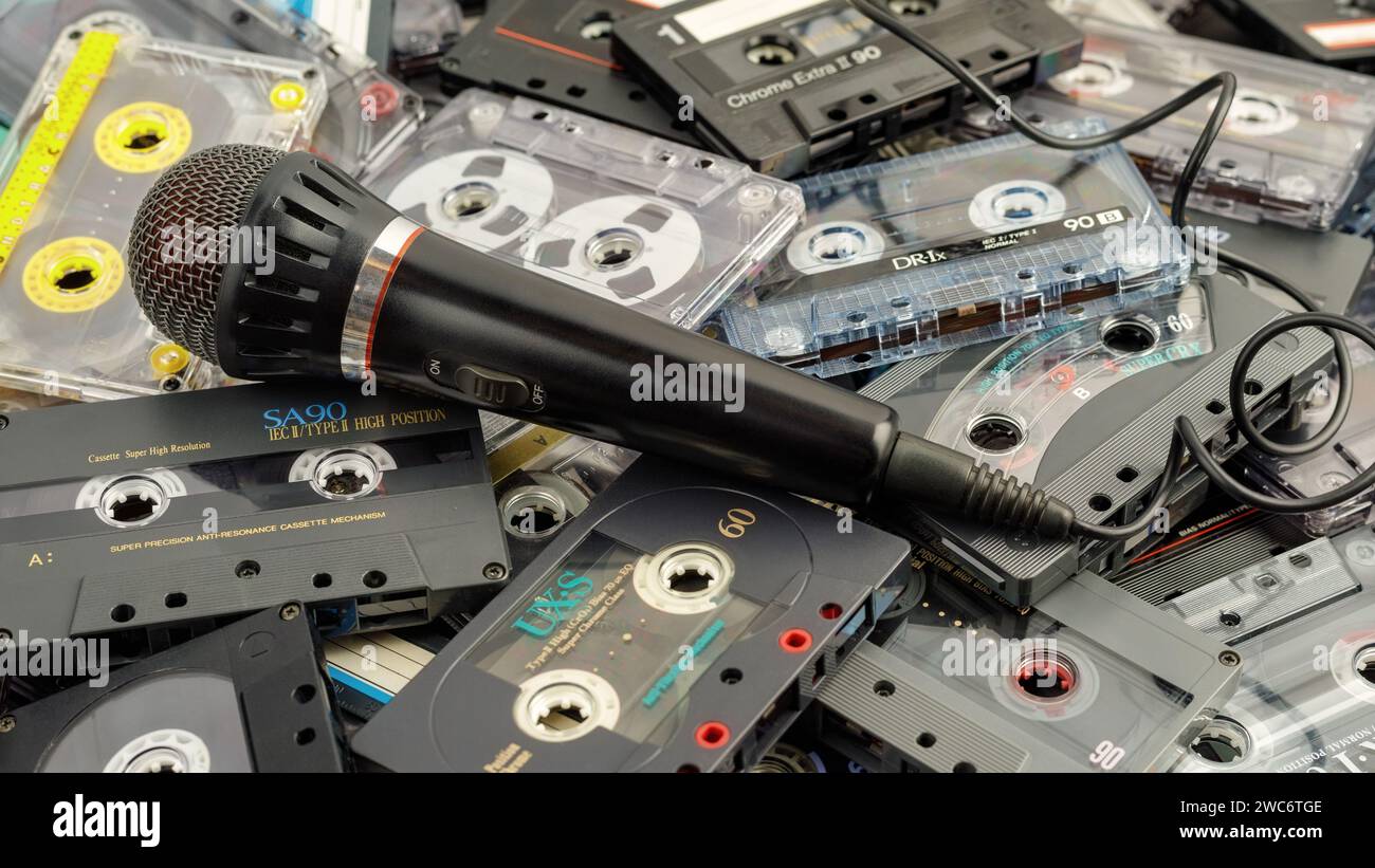 Nostalgia 80's, karaoke microphone on audio cassettes background. Hobby, voice recording at home