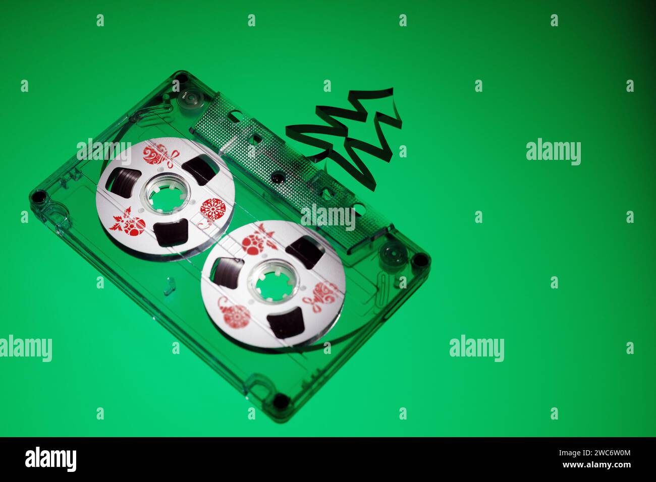 1980's audio cassette with white discs decorated with chritmas toys pictures on a green background with free space for Christmas themed text. Stock Photo