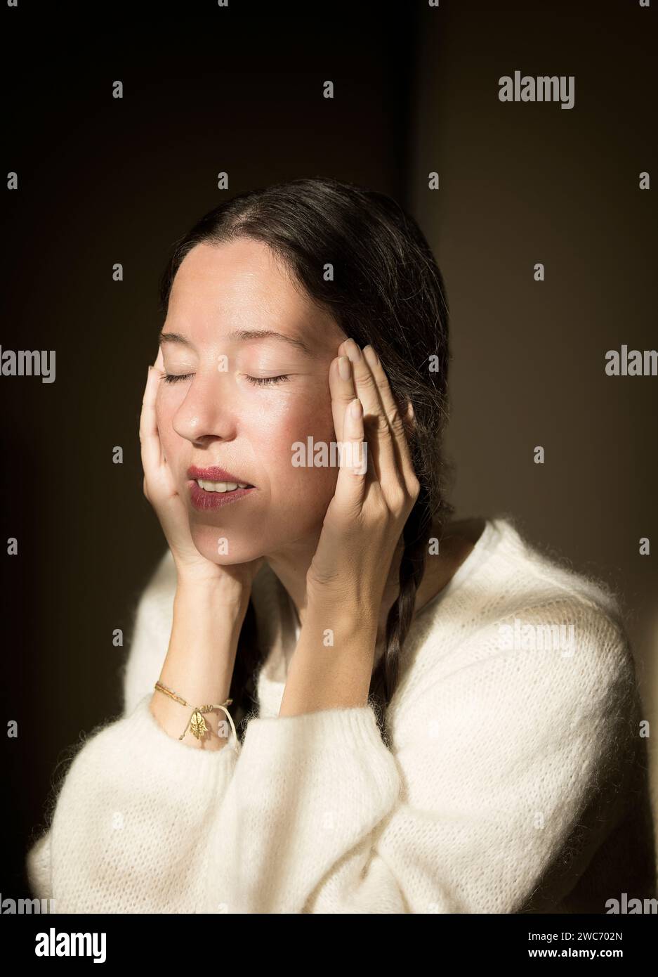 woman sitting on a chair with white wool sweater in thoughtful attitude IV,france Stock Photo