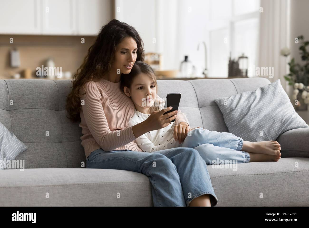 Positive mom teaching sweet child girl to use online service Stock ...
