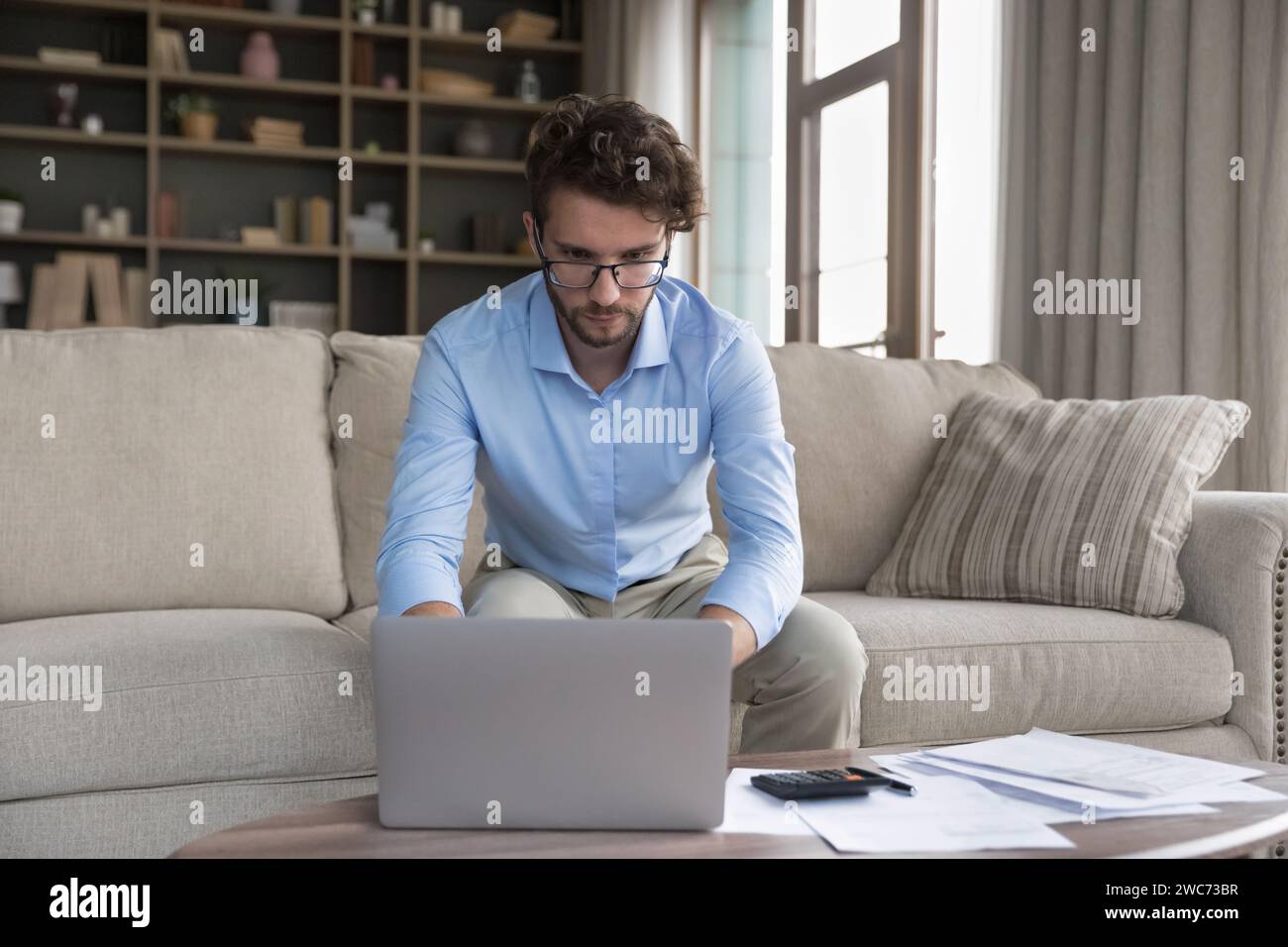 Serious man sit on sofa do accounting work from home Stock Photo