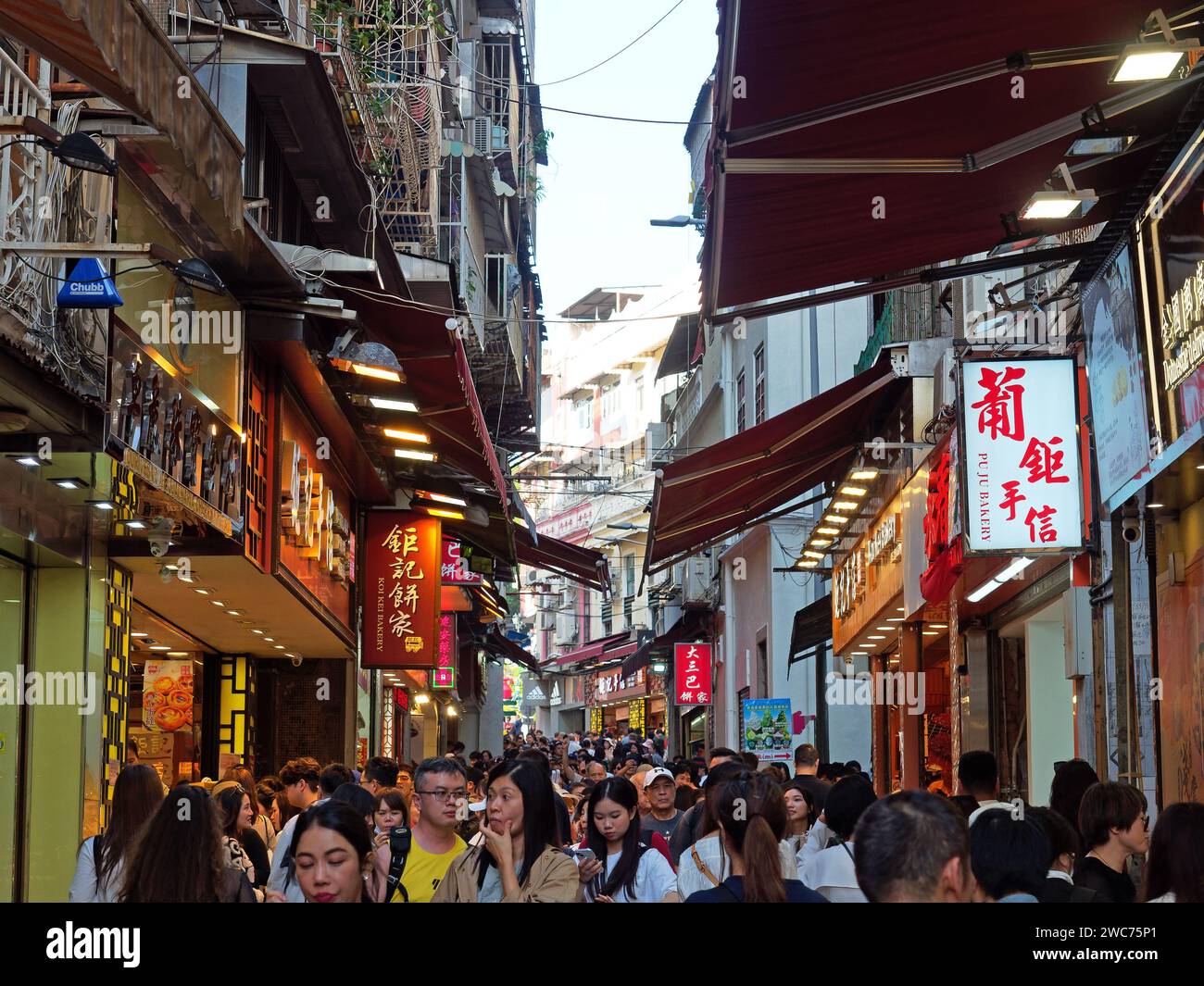 Typical busy narrow street in Macau congested with people, shops, bars, and restaurants Stock Photo
