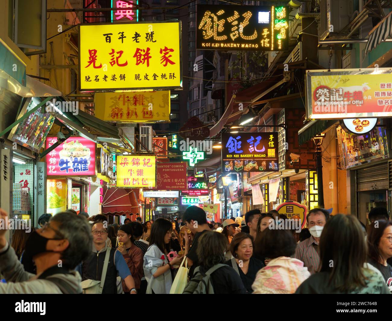 Narrow street  in the Macau lined with bars and restaurants busy and crowded with shoppers and diners at night Stock Photo