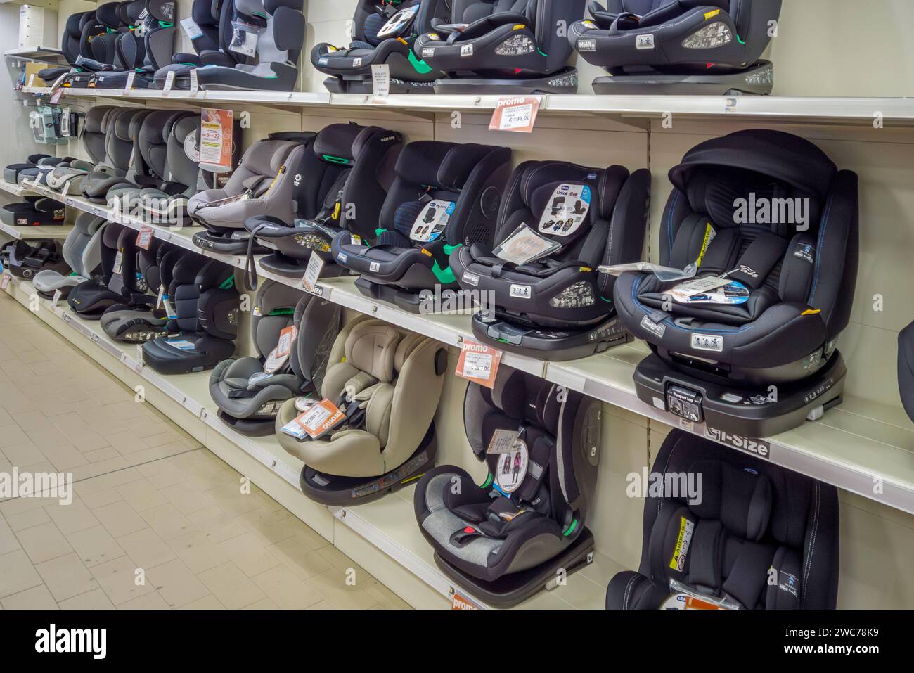 Italy - December 19, 2023: safety car seat for baby of various and different types displayed on shelves for sale in baby store Stock Photo