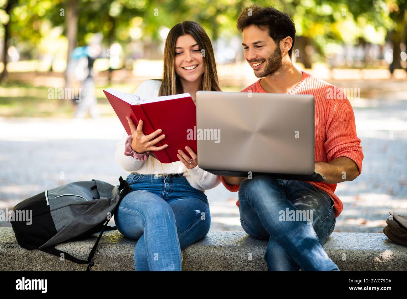 Two students studying together sitting on a bench outdoor Stock Photo