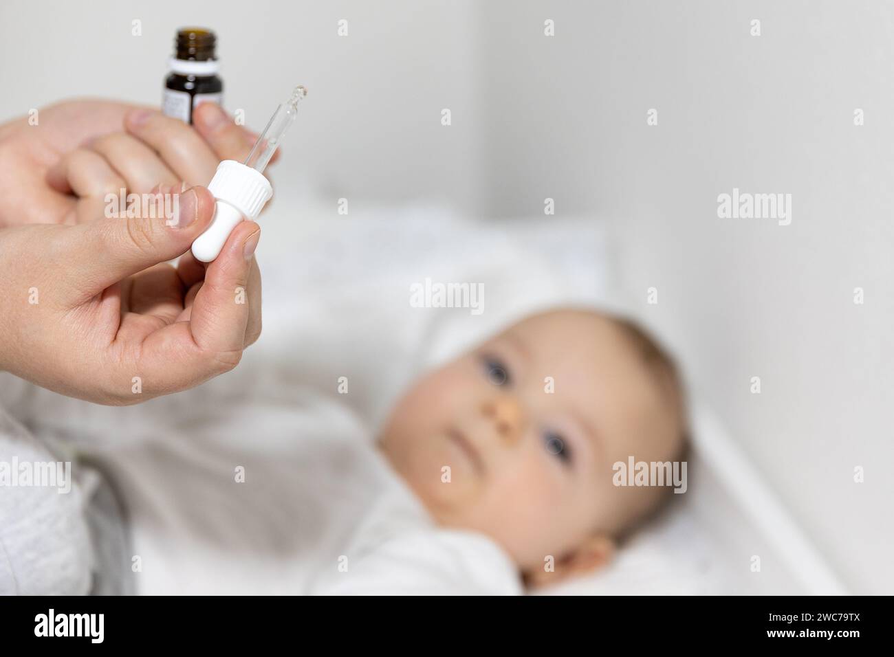 Mom giving vitamin D3 to newborn baby for care of the proper