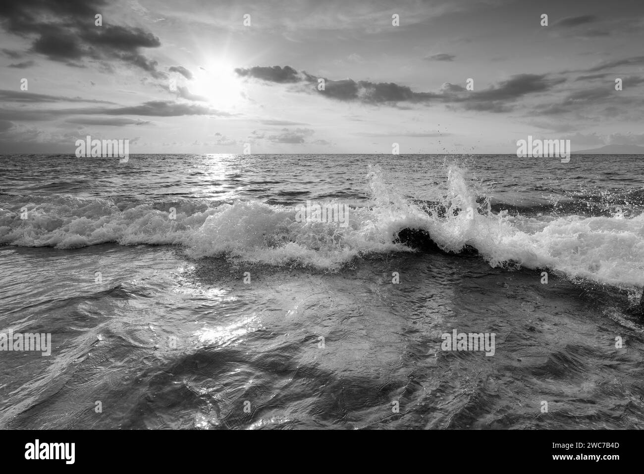 An Ocean Wave Is Splashing Droplets Of water With Sun Rays Breaking Through Clouds Black And White Image Stock Photo