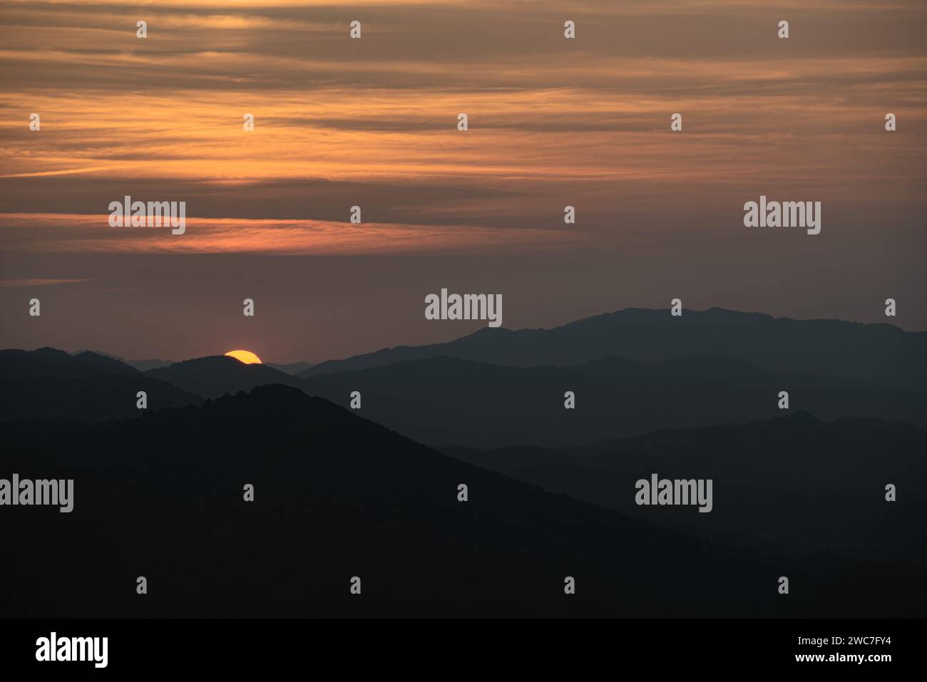 A breathtaking sunset casts a warm glow over rolling hills and ...