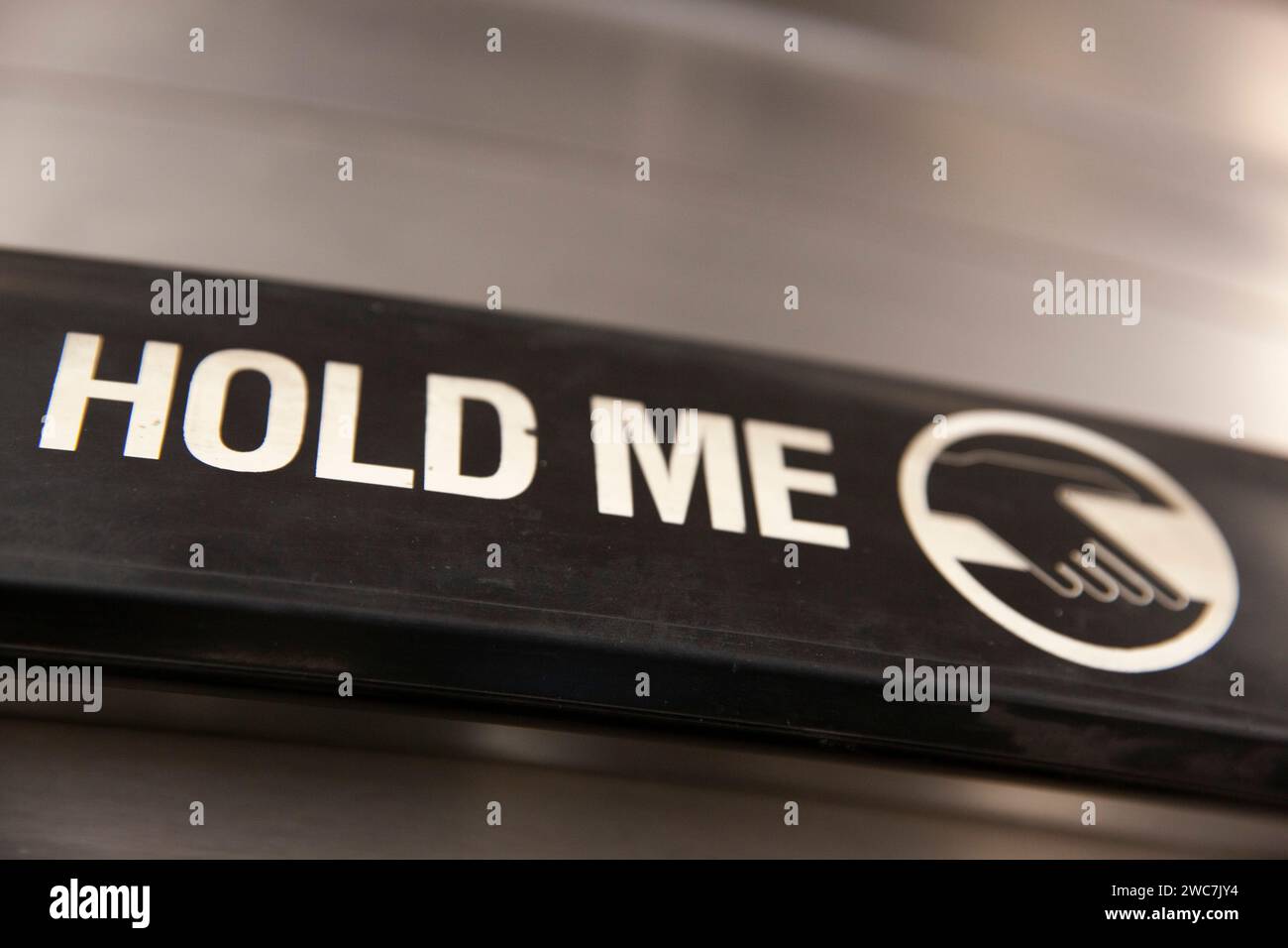'Hold Me' is written on the moving handrail of an escalator at Charing Cross station in  London to encourage people to travel safely. Since covid peop Stock Photo