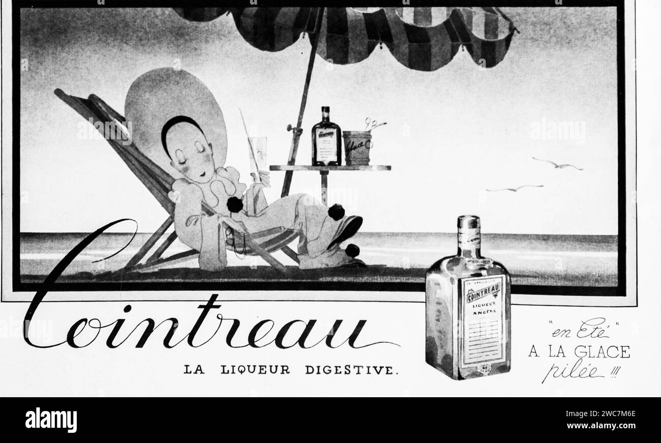 This classic black and white 1930 advertisement depicts a contented woman lounging in a beach chair, enjoying Cointreau, with an emphasis on leisure and refreshment. Stock Photo