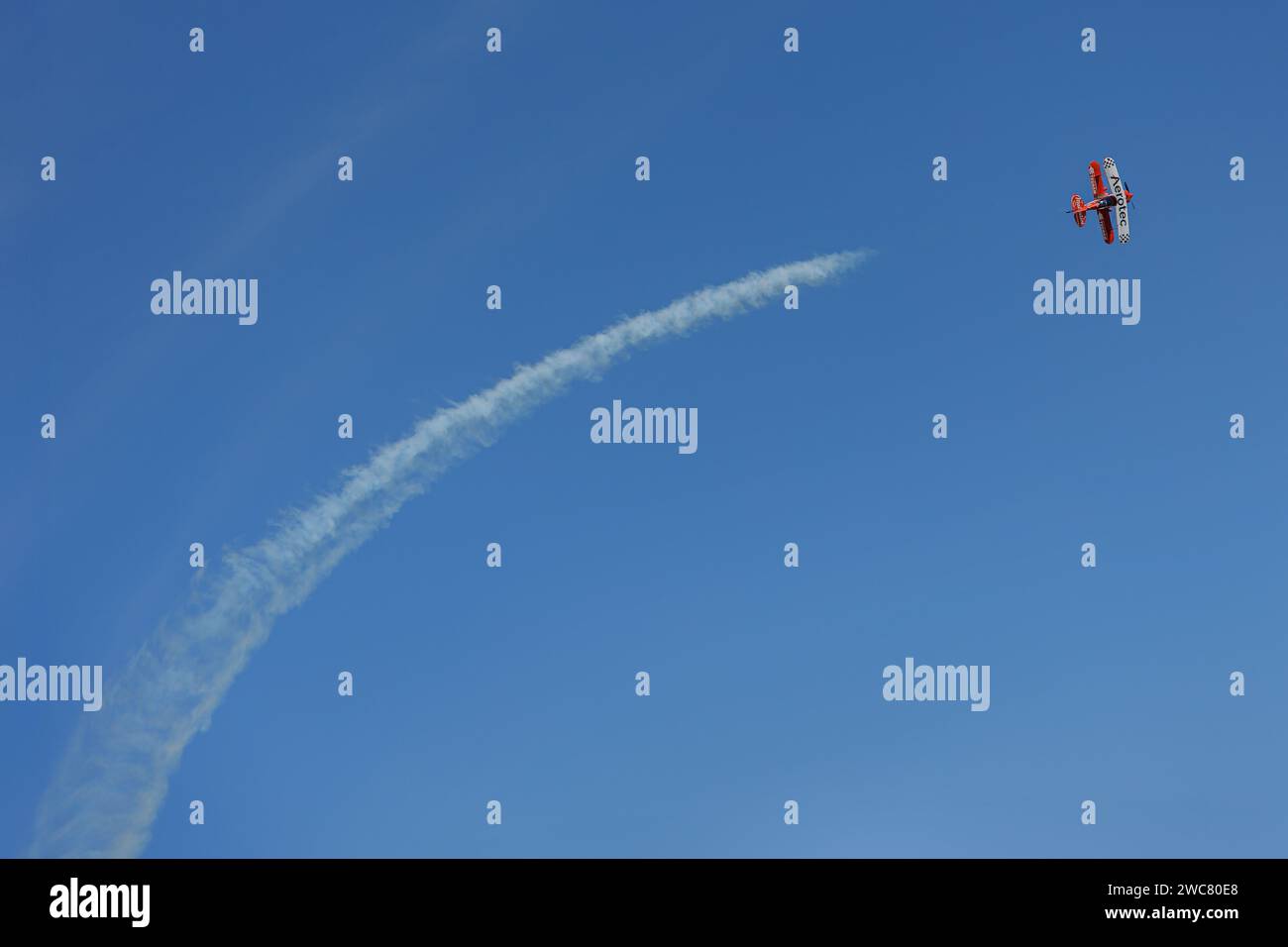 Mar del Plata, Argentina - January 14th, 2023: Biplane airplane doing stunts in the sky and releasing smoke. Stock Photo
