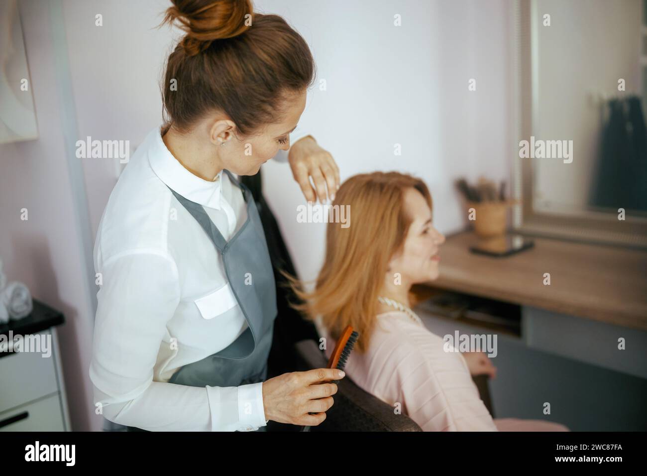 40 years old hair salon employee in modern hair studio with hairbrush