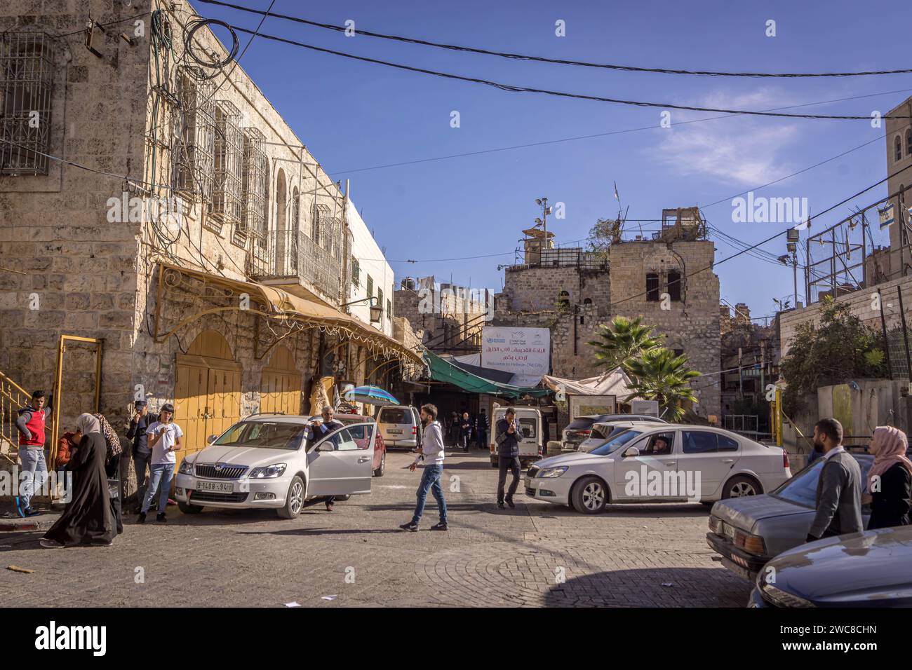 The Palestinian people walking in the dowtown of Hebron, West bank (Palestine) with the old stone buildings and sign 'Welcome to Hebron Old City' (in Stock Photo