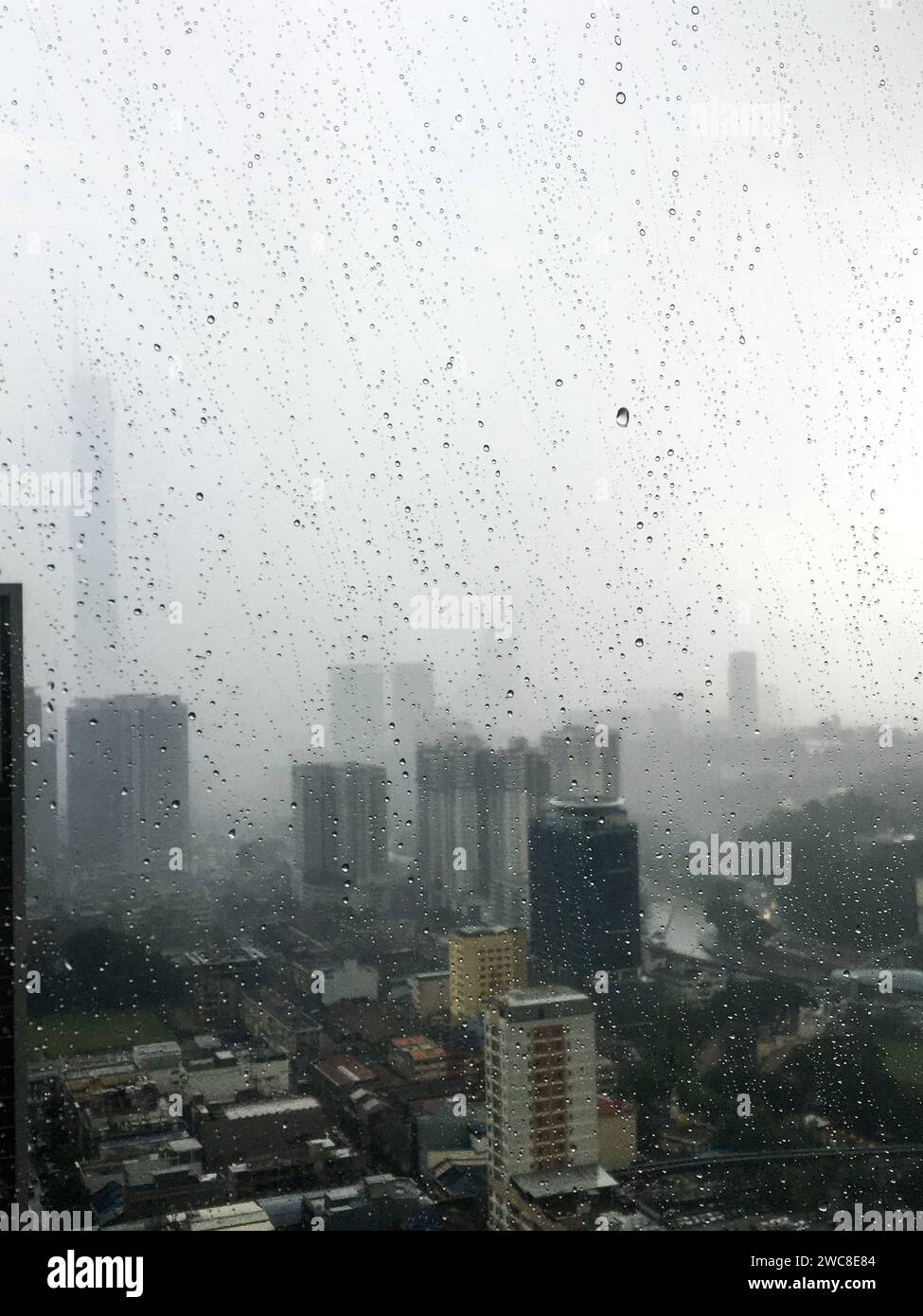 Drops of rain on the office window. Aerial view of  Malaysia. blur urban skyline background. rainy season concepts. Stock Photo