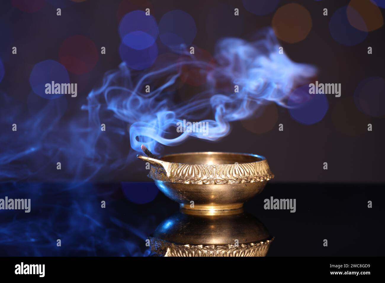 Blown out diya on dark background with blurred lights. Diwali lamp Stock Photo