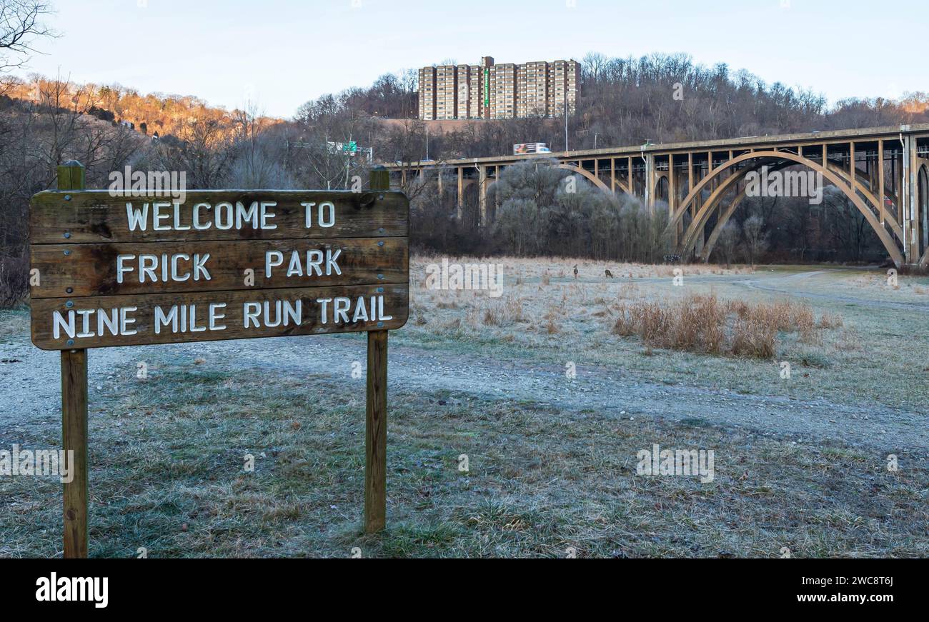 A welcome sign in Frick Park with two deer in a field behind it in ...