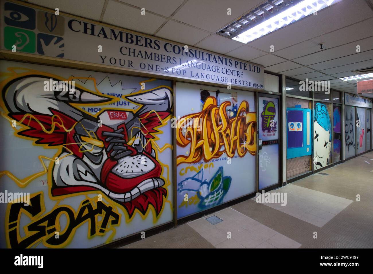 Inside Peace Centre, a commercial building, abandoned shopfronts covered in graffiti art or spray paint by local artists. Singapore. Stock Photo