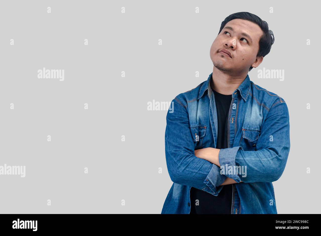 Young Asian Man thinking about question, pensive expression. while hand arms folded. On isolated background Stock Photo