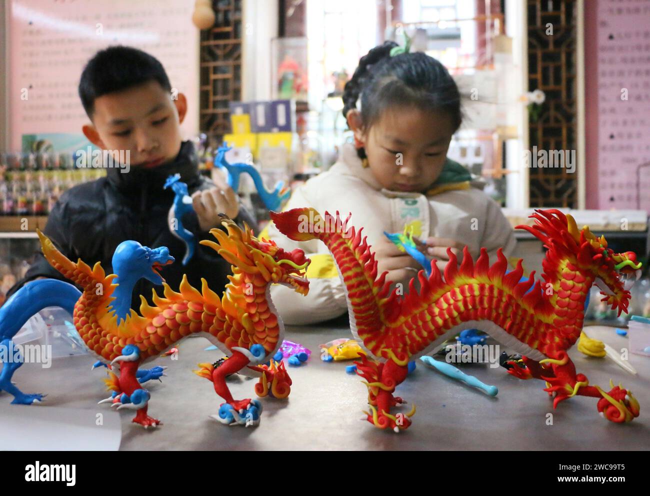 ZOUCHENG, CHINA - JANUARY 14, 2024 - Two children knead a dough sculpture dragon in Zoucheng city, Shandong province, China, Jan 14, 2024. Stock Photo