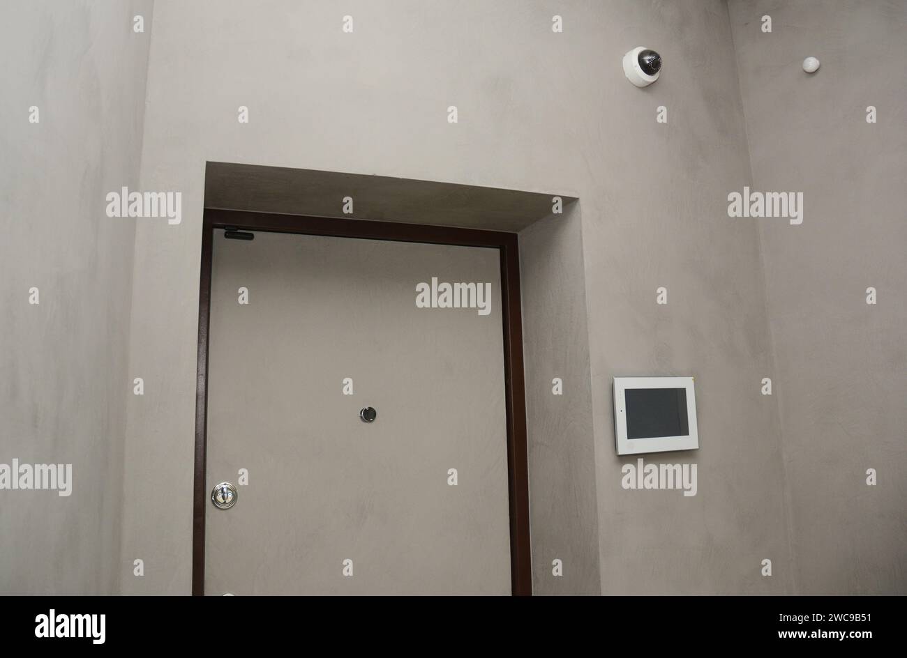Modern house entrance door interior with  smart house system, security camera, smoke alarms and fire detection. A smart home allows homeowners to cont Stock Photo