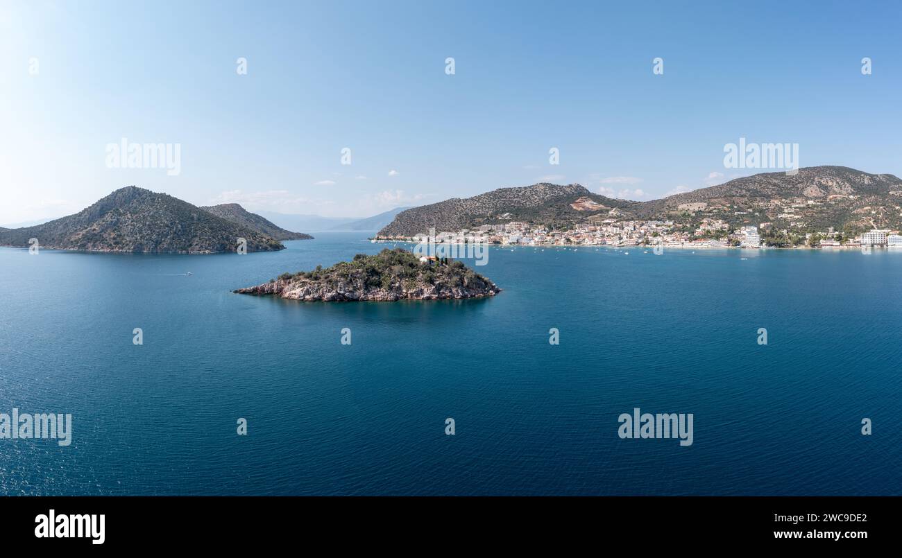 Greece, Tolo near Nafplio, Argorida, Peloponnese. Aerial drone panoramic view of village, small island, moored boat at port, sea, blue sky. Space Stock Photo