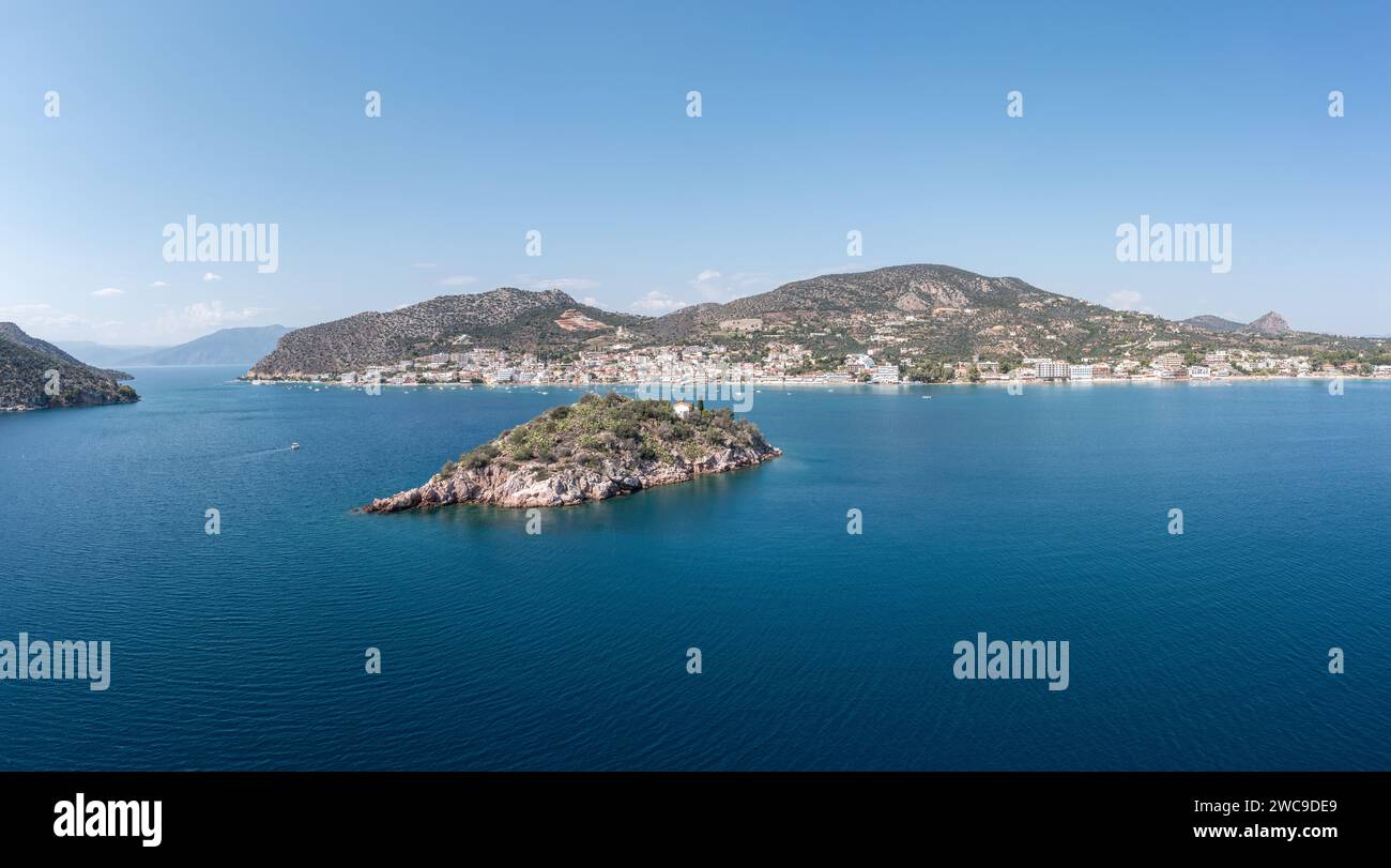 Tolo near Nafplio, Argorida, Peloponnese, Greece. Aerial drone panoramic view of village, small island, moored boat at port, sea, blue sky. Space Stock Photo
