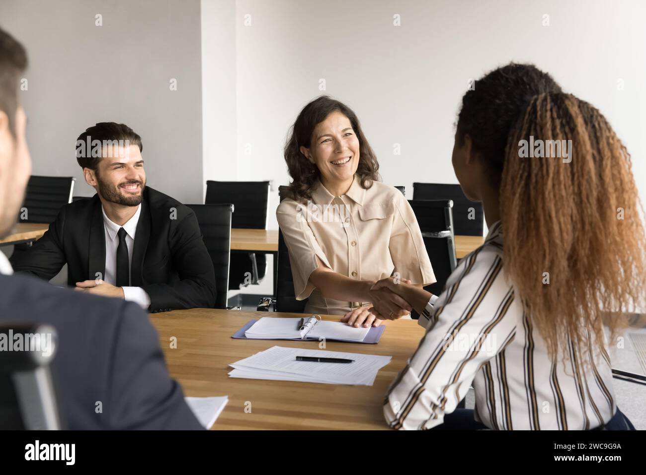 Young African business professional woman shaking hands with colleague woman Stock Photo