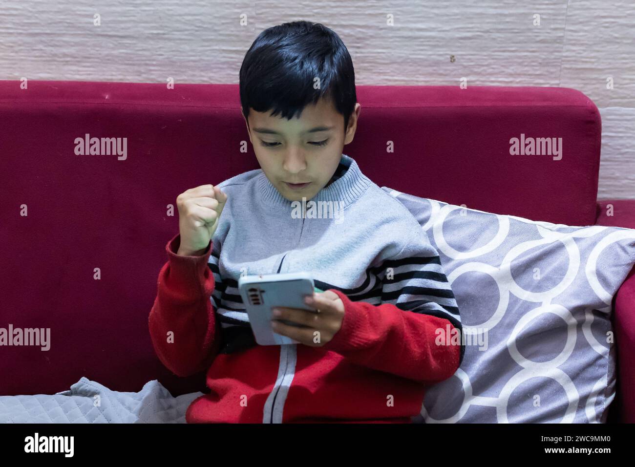 young kid facial expression after wining mobile online game at home at night Stock Photo