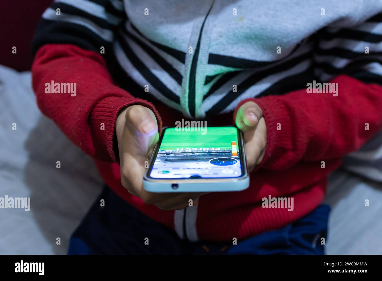 child finger tapping mobile phone screen while playing online game at