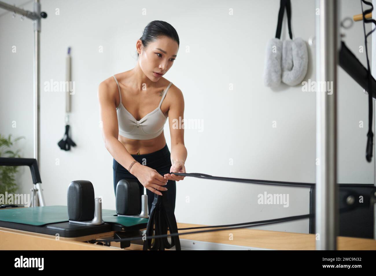 Fit young woman adjusting straps in exercise machine Stock Photo