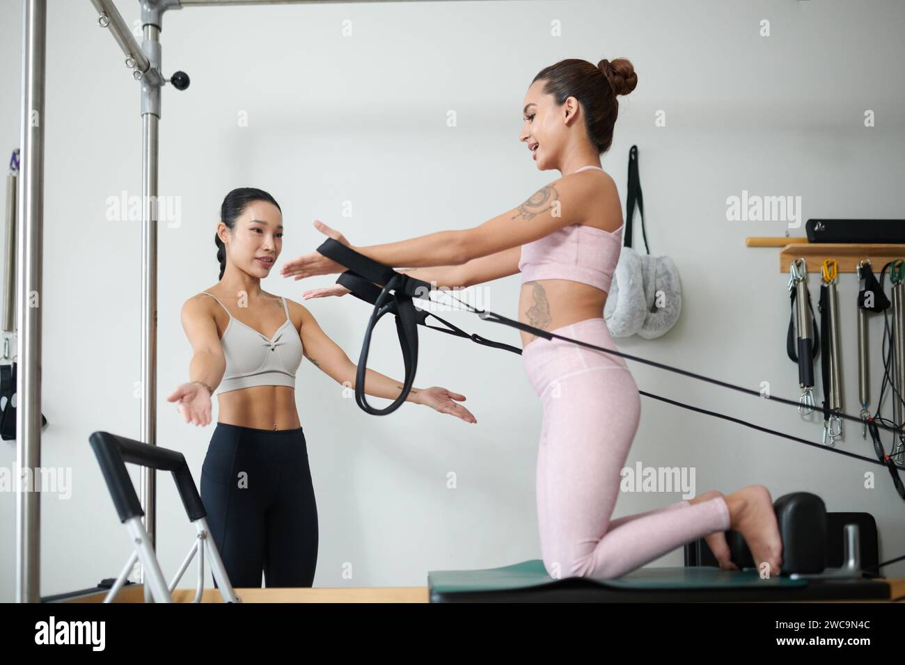 Fitness coach explaining client how to hold straps when work out in exercise machine Stock Photo