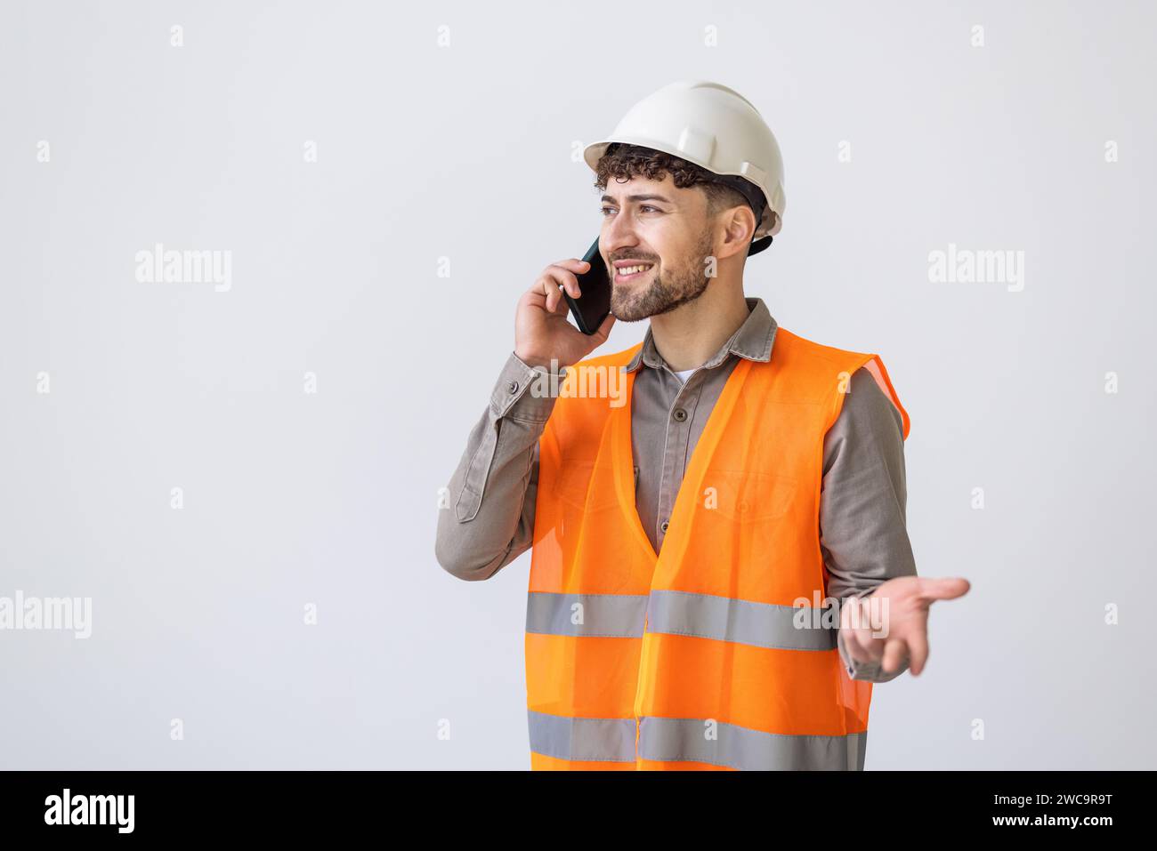 Construction worker using cell phone.Three quarter length studio shot isolated on white. Stock Photo
